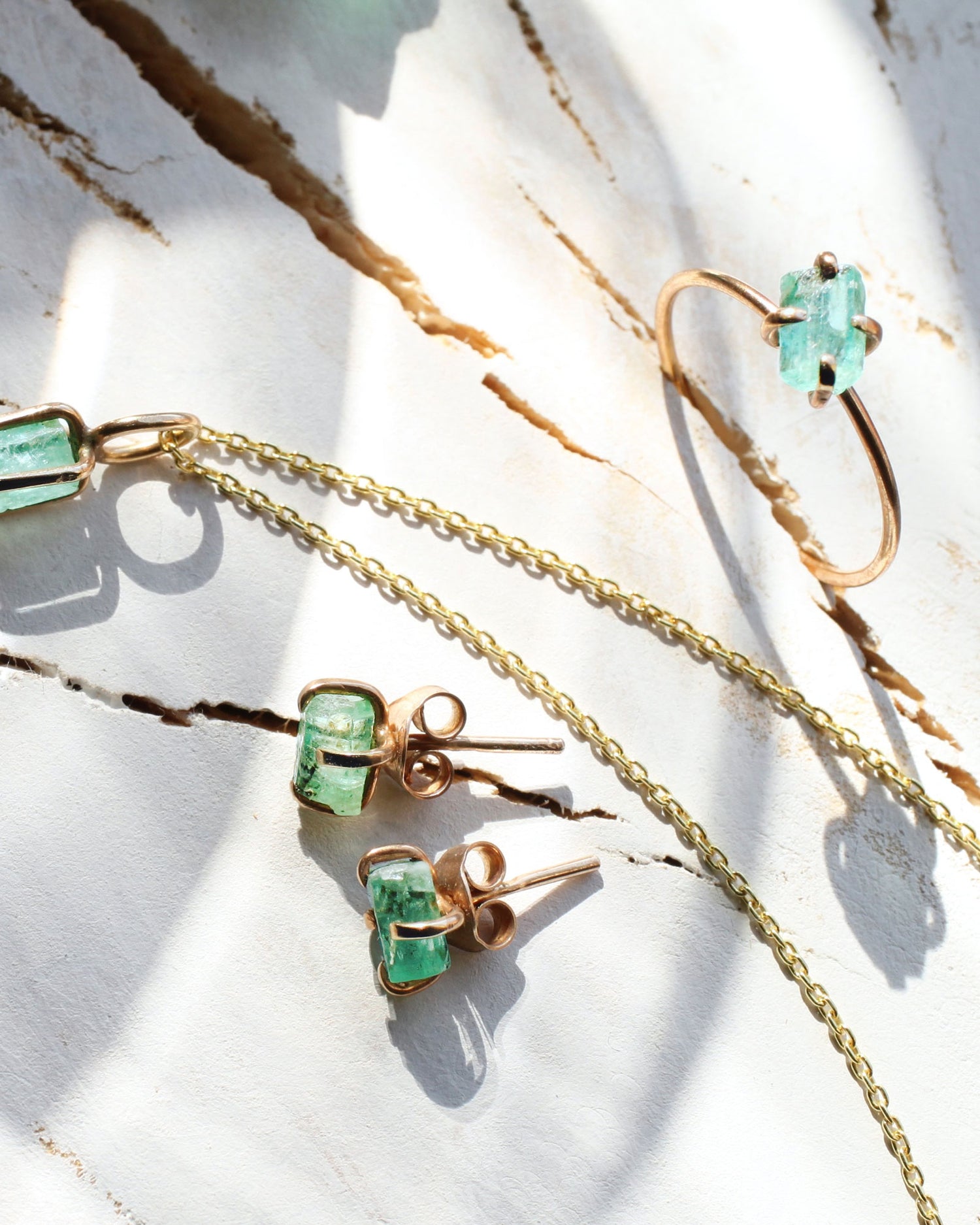 Golden jewellery with rough emeralds on a wooden backround
