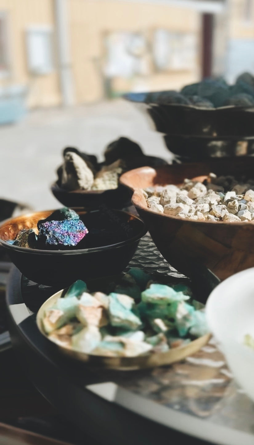 Decorative setting with bowls containing stones and crystals on a table.