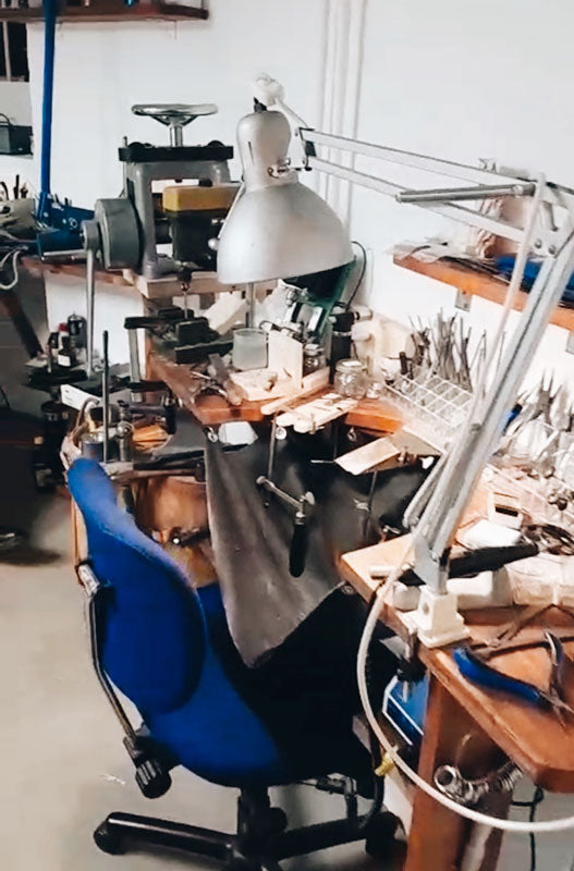 Goldsmith Workshop with various tools and equipment on a desk, featuring a blue chair.