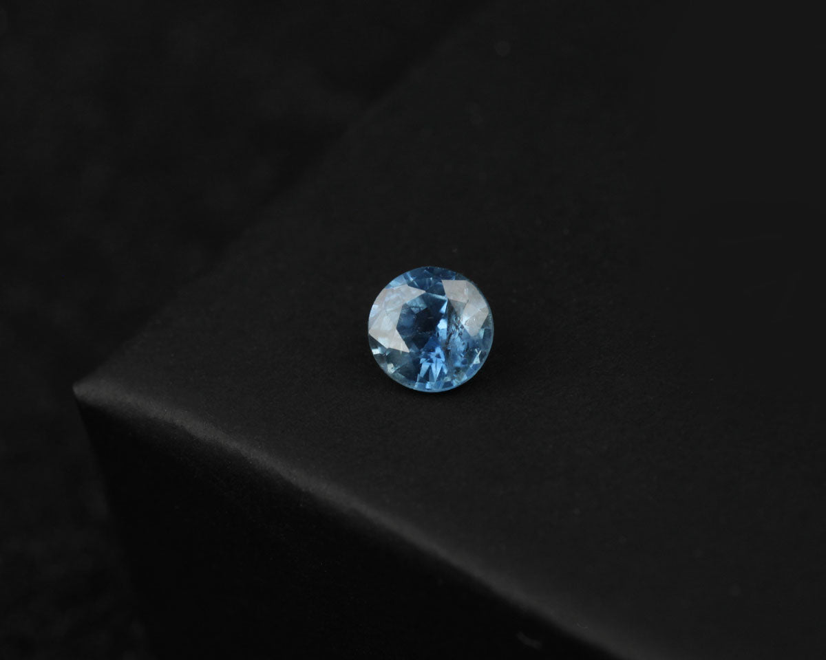 Blue faceted sapphire on a dark textured surface