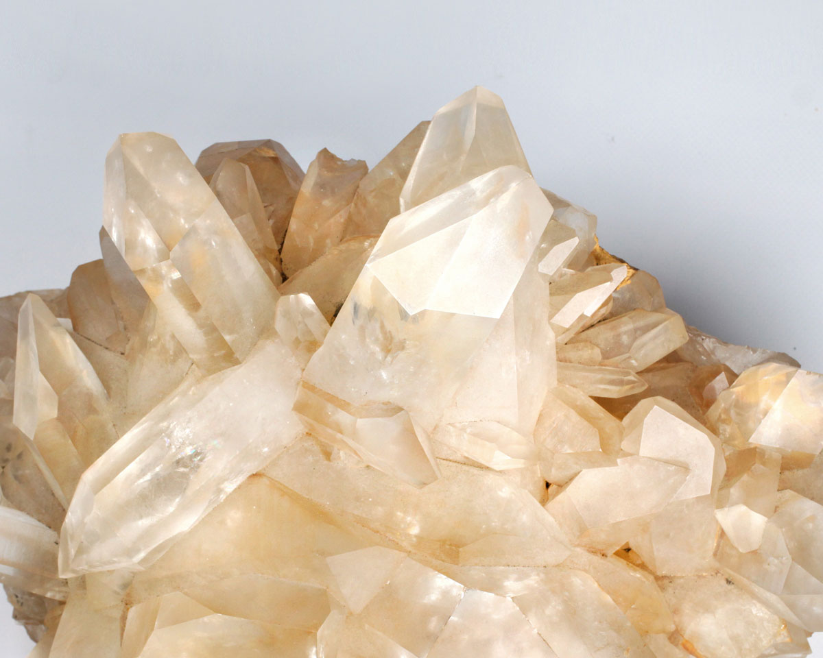 Close-up of tangerine quartz crystal formation on a light gray background