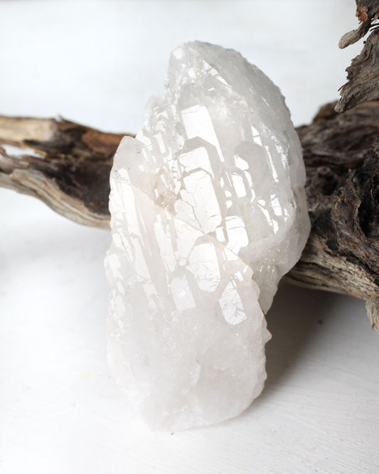 Rock crystal on a white background with a natural wood branch